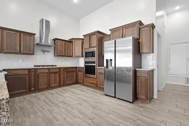a large kitchen with stainless steel appliances kitchen island granite countertop a sink counter space and cabinets