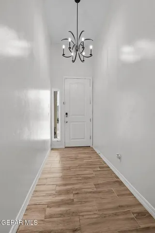 a view of an empty room with wooden floor and fan