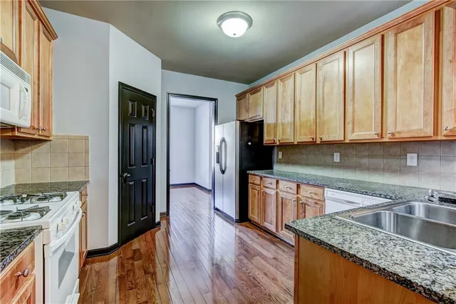 a kitchen with stainless steel appliances granite countertop a refrigerator a sink dishwasher and wooden cabinets with wooden floor