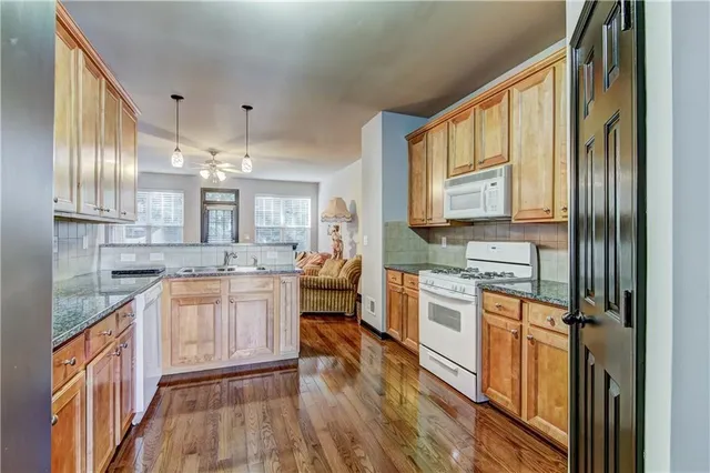 a kitchen with stainless steel appliances granite countertop a refrigerator a stove and a sink with wooden floor