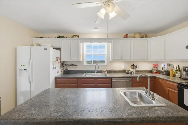a kitchen with granite countertop a stove sink and refrigerator