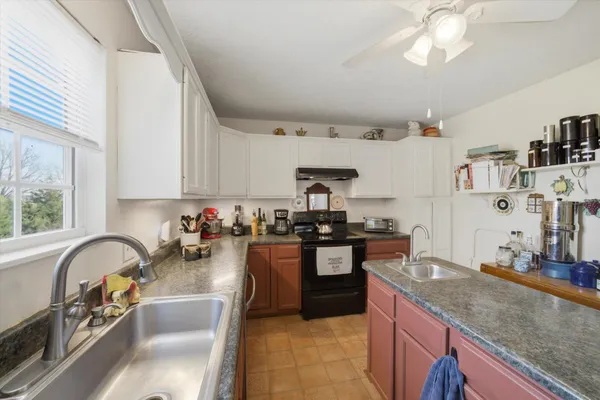 a kitchen with kitchen island granite countertop a sink stove top oven and cabinets