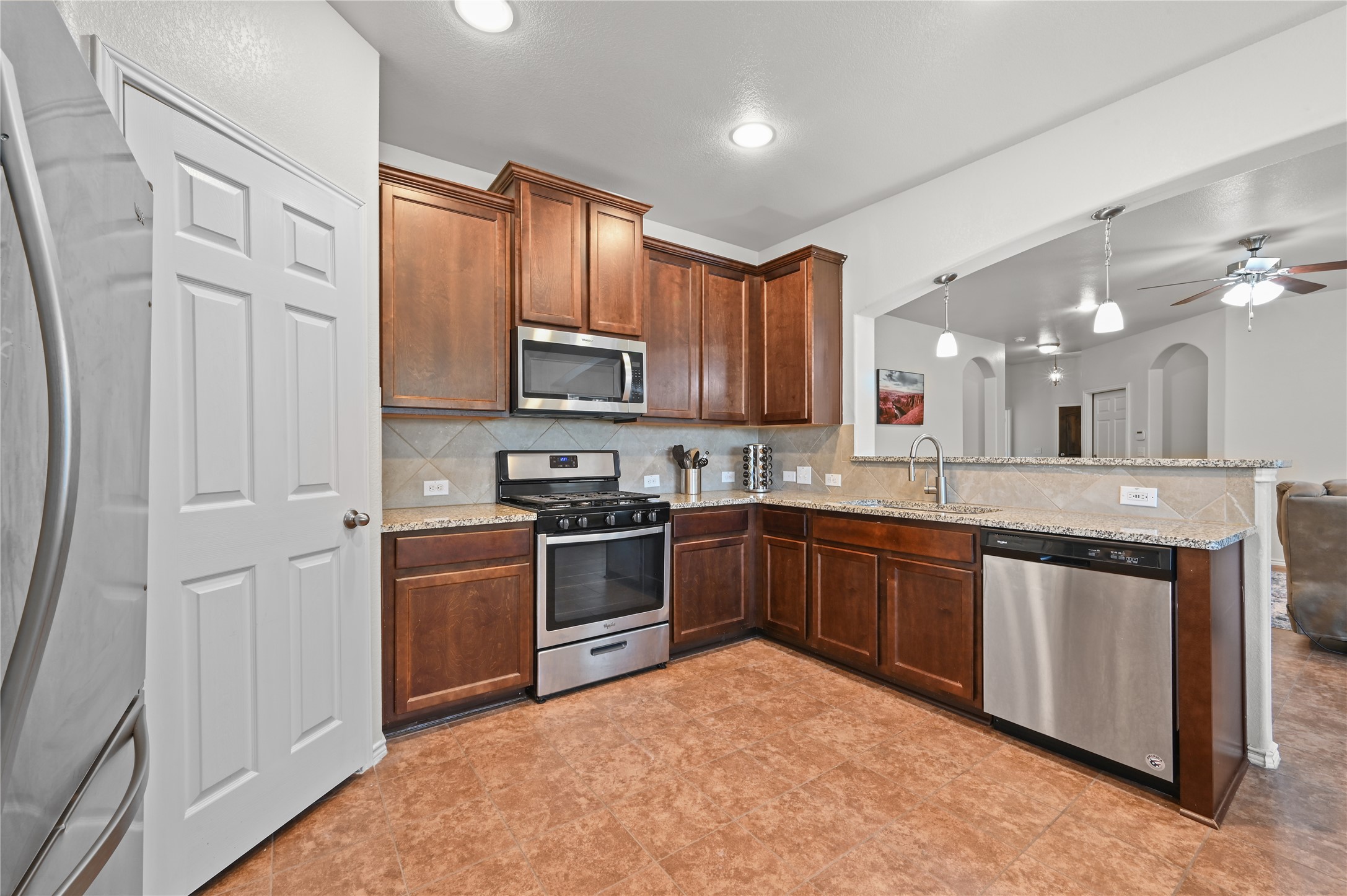 303 Limerick Road Buda, TX 78610 - Photo 8 of 23 Kitchen featuring recessed lighting, wood cabinetry, granite countertops, tile backsplash, and stainless steel appliances