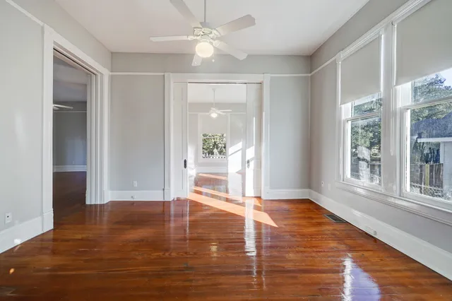 a view of an empty room with wooden floor and a window