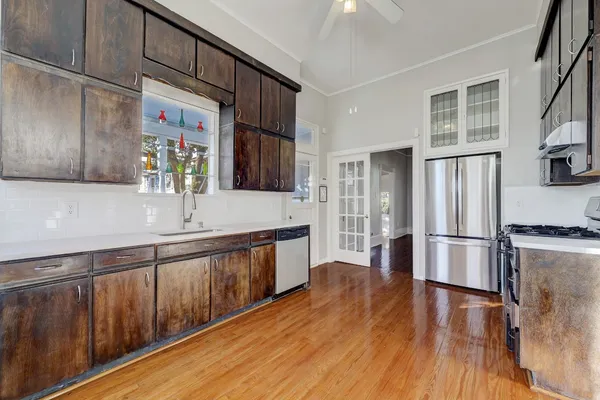 a kitchen with stainless steel appliances hardwood floor sink stove and wooden cabinets