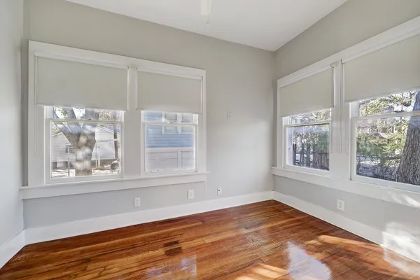 a view of an empty room with window and wooden floor