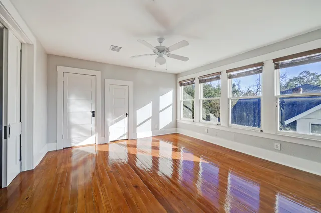 a view of an empty room with a window and wooden floor