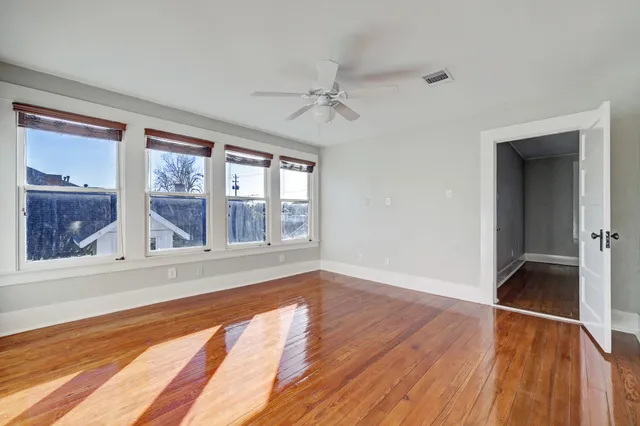 a view of an empty room with wooden floor and a window