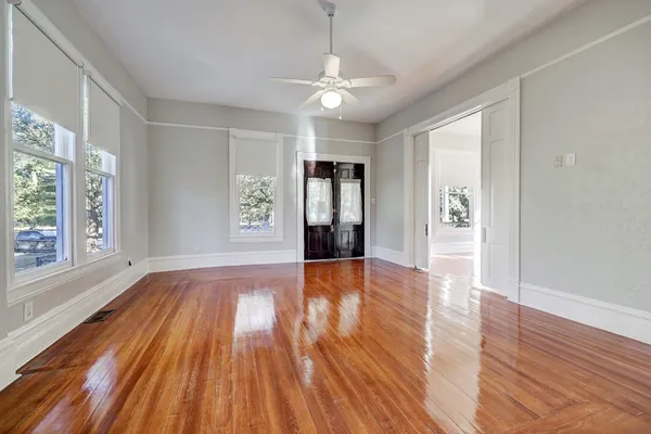 a view of an empty room with wooden floor and a window