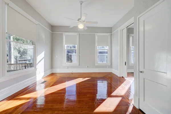 a view of empty room with wooden floor and fan