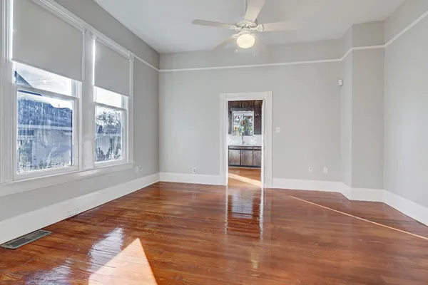 a view of an empty room with wooden floor and a window
