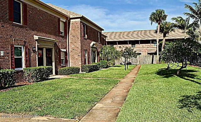 a front view of a house with a yard and potted plants