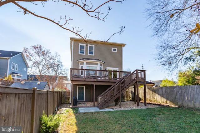 a view of a house with a small yard and a wooden deck