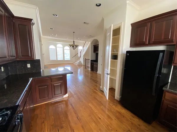 a kitchen with stainless steel appliances granite countertop a refrigerator a stove top oven and wooden floors