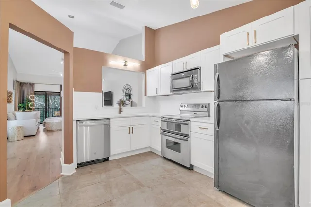 a kitchen with white cabinets and stainless steel appliances