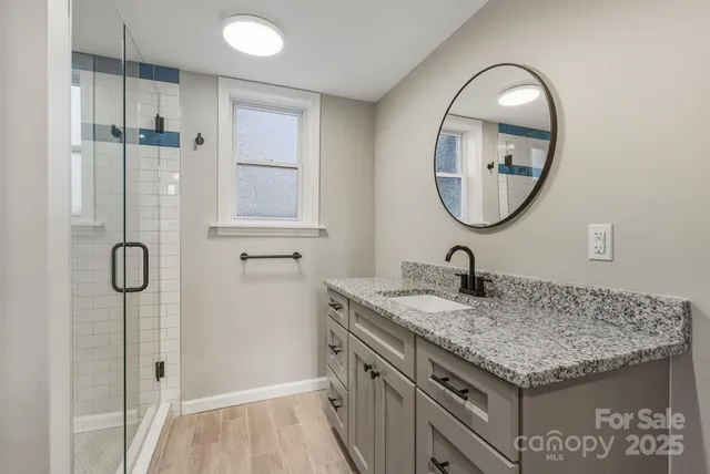 a bathroom with a granite countertop sink a mirror and a shower