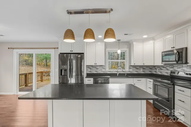 a kitchen with stainless steel appliances granite countertop a sink a stove and microwave