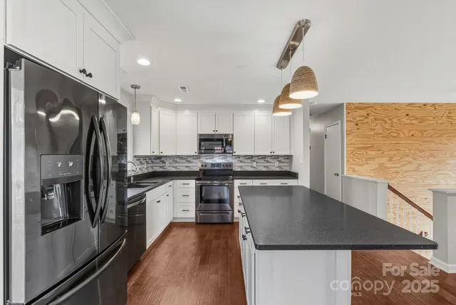 a kitchen with stainless steel appliances granite countertop a sink a stove and a refrigerator
