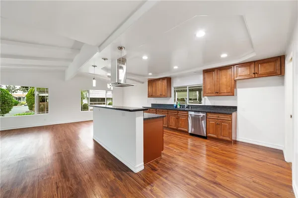 a kitchen with kitchen island granite countertop wooden floors stainless steel appliances and a sink