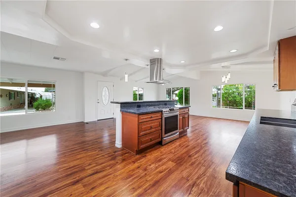 a kitchen with stainless steel appliances kitchen island wooden floors wooden cabinets and entryway