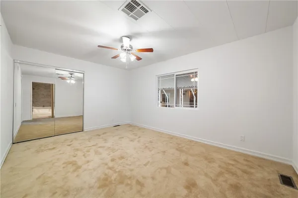 an empty room with windows and ceiling fan