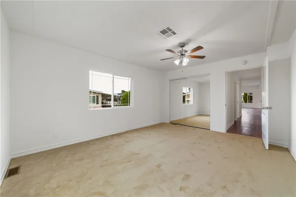 an empty room with chandelier fan and windows
