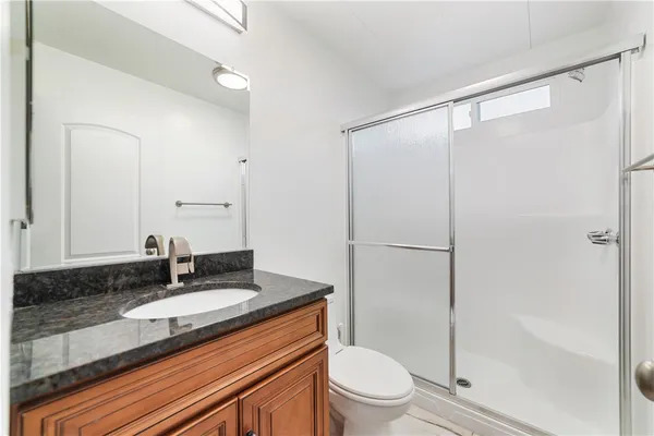 a bathroom with a granite countertop sink toilet and shower