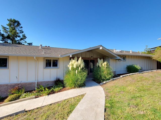 a front view of a house with a yard and potted plants