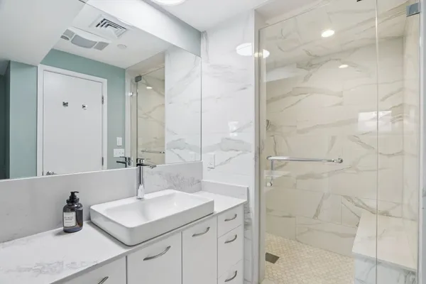 a bathroom with a sink shower and a mirror