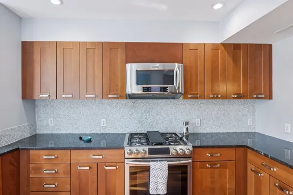 a kitchen with stainless steel appliances granite countertop a stove a sink and a microwave