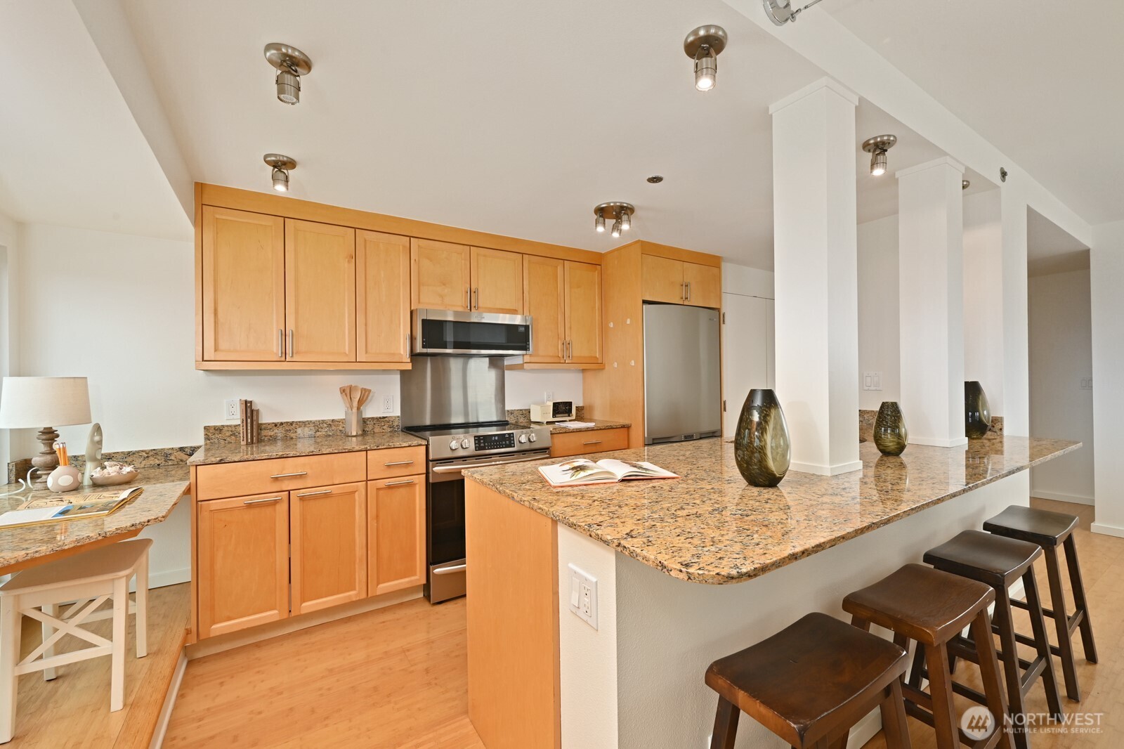 121 Vine Street, Unit 703 Seattle, WA 98121 - Photo 10 of 37 a kitchen with granite countertop kitchen island sink stove and white cabinets