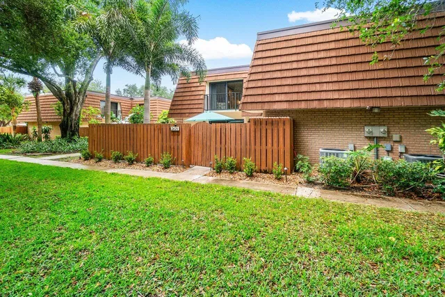 a view of a house with a yard and large tree