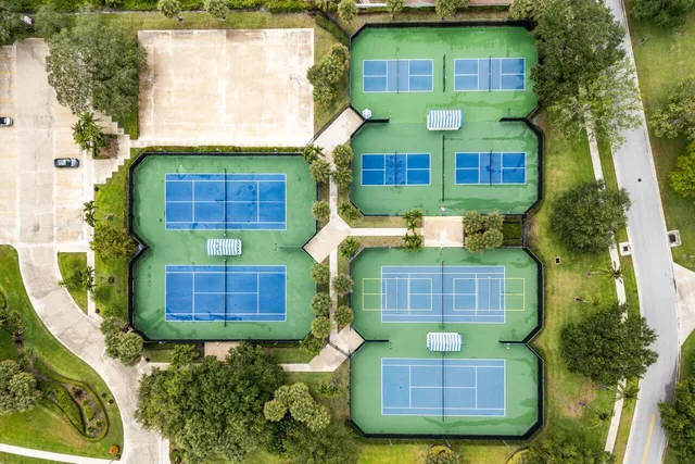 a view of brick house with a yard potted plants and large tree