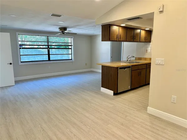 a living room with stainless steel appliances kitchen island granite countertop a stove and a large window