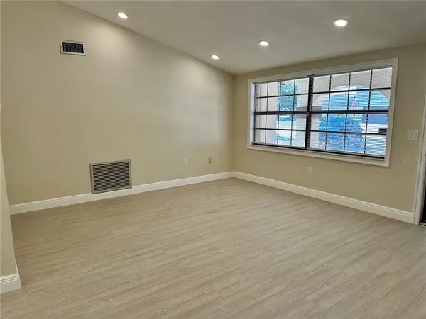 an empty room with wooden floor and windows