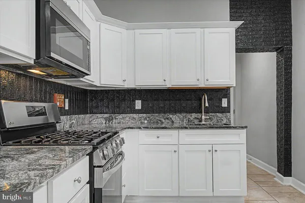 a kitchen with white cabinets and stainless steel appliances