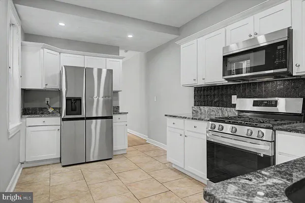 a kitchen with stainless steel appliances granite countertop a stove a refrigerator and a microwave
