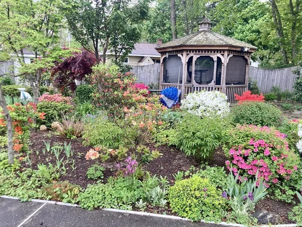 a front view of a house with a yard and fountain in middle of flower