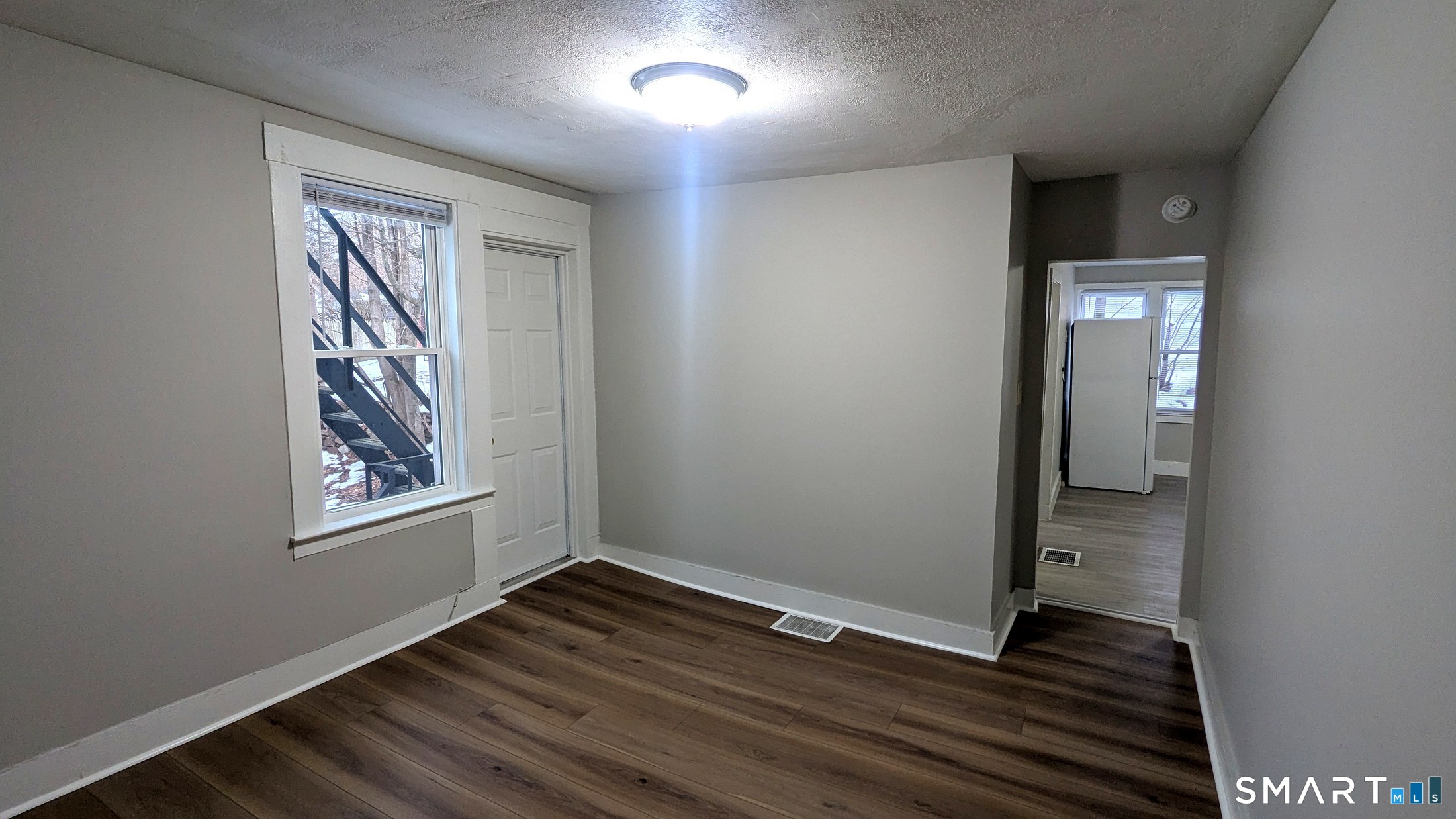 an empty room with wooden floor and windows