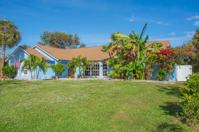 a view of a house with a big yard and palm trees