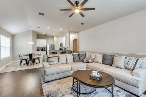 a living room with furniture kitchen view and a chandelier