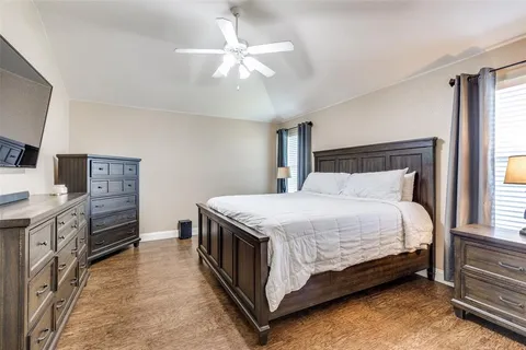 a spacious bedroom with a bed and a flat tv screen on dresser