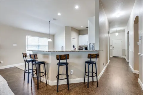 a kitchen with stainless steel appliances kitchen island granite countertop lots of white cabinets and wooden floor