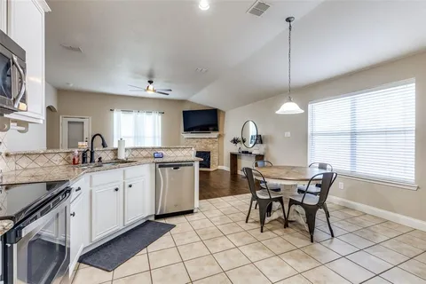 a kitchen with granite countertop cabinets a sink dining table and chairs