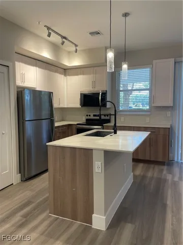 a kitchen with stainless steel appliances a refrigerator a sink a stove a microwave and wooden floor