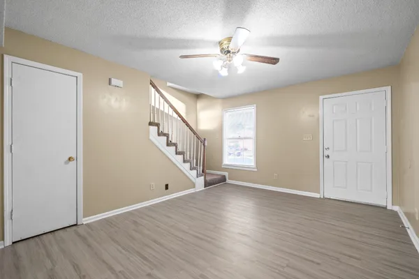 a view of an empty room with wooden floor and staircase
