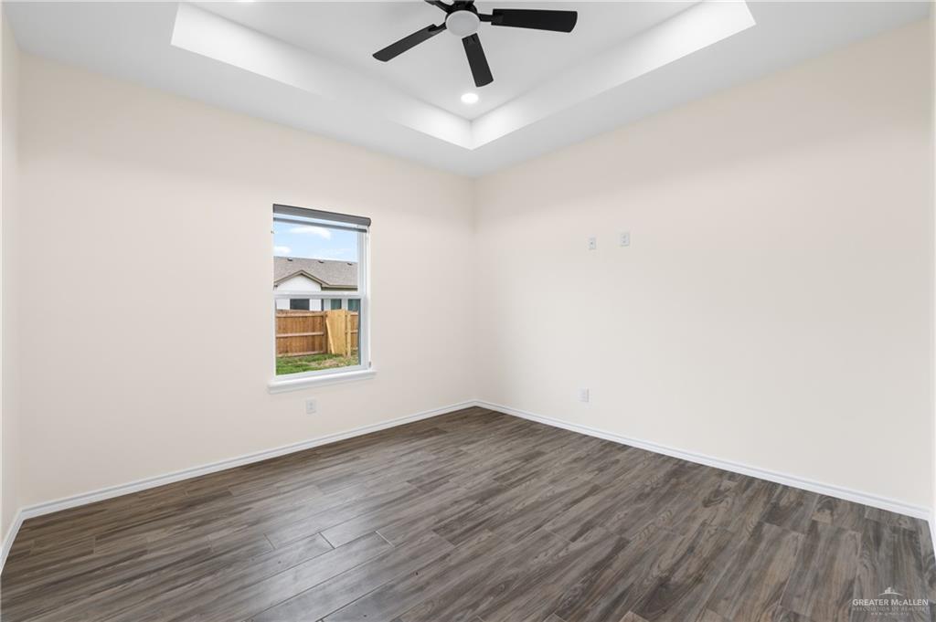 18054 Spruce Street Combes, TX 78552 - Photo 17 of 25 Room featuring wood-finish flooring, a tray ceiling, and an installed ceiling fan with lighting
