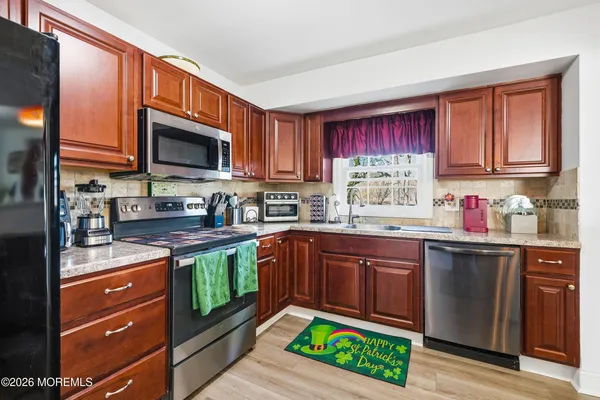 a kitchen with stainless steel appliances granite countertop a stove sink microwave and window
