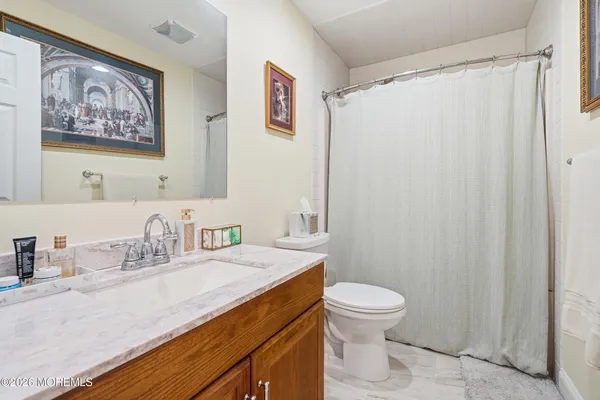 a bathroom with a granite countertop sink a toilet and a shower