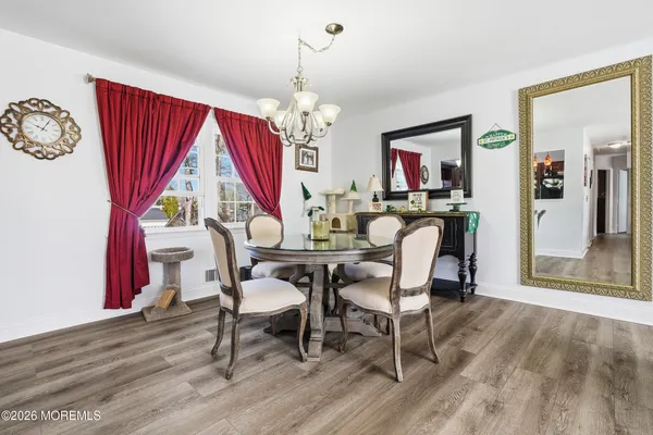 a dining room with wooden floor a chandelier a wooden table and chairs